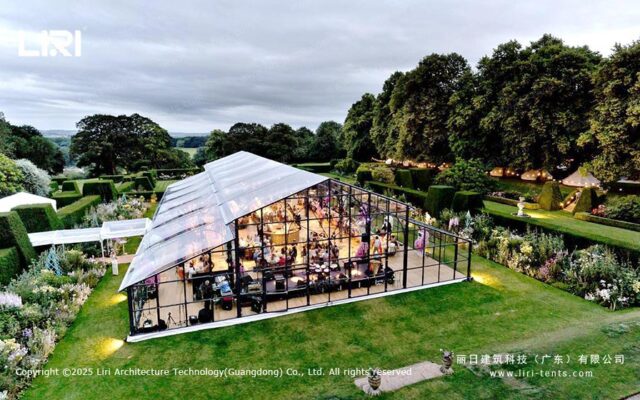 Außenansicht eines Garten-Events in einem Orangerie-Zelt mit Glaswänden und Abendbeleuchtung