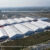 Luftaufnahme eines großen Ausstellungszeltkomplexes aus Aluminiumkonstruktionen, in dem eine Weltmesse stattfindet